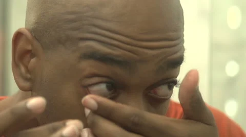 A black man, in reflection, inserts two contact lenses Stock Footage 44219184
