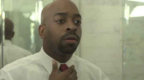 A black man, in reflection, puts on a tie and jacket. Stock Footage 44235366
