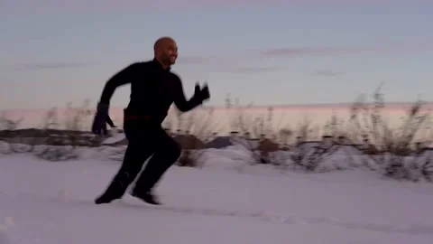 Black man running in the snowy road with amazing background with sunset Stock Footage 146413045