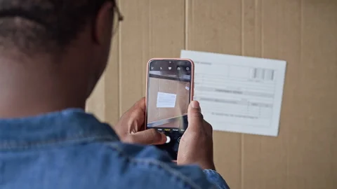 Black Man Scanning Shipping Label on Cardboard Box with Smartphone Stock Footage 337307198