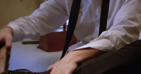 Black man shining shoes while sitting on a bed 스톡 동영상 127257652