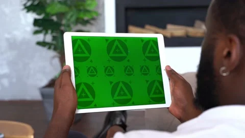  black Man sitting and holding in hands portable tablet with green screen Stock Footage 197442451