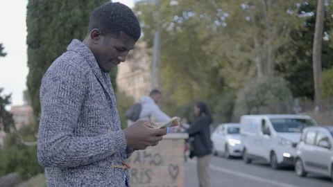 Black man sitting texting on mobile phone on the street Stock-Footage 214659110