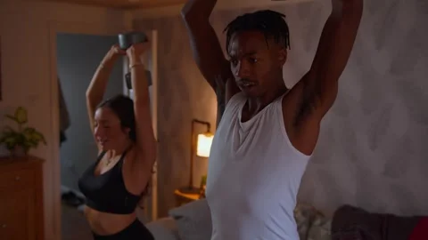 Black man smiles while exercising at home with wife  Stock Footage 292244910