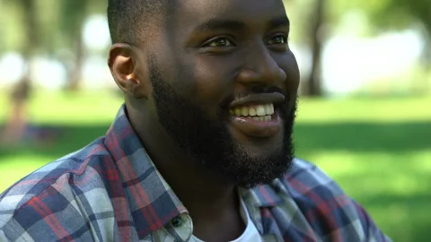 Black man smiling and drinking wine, gathering with friends in park, relax time Stock Footage 100685908