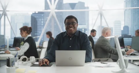 Black Man Smiling And Working On Laptop In Diverse Office Stock Footage 251643579