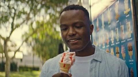 Black man smiling while eating ice cream Stock Footage 264035628