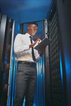 Black man, tablet and typing for inspection in server room with cybersecurity Stock Photos