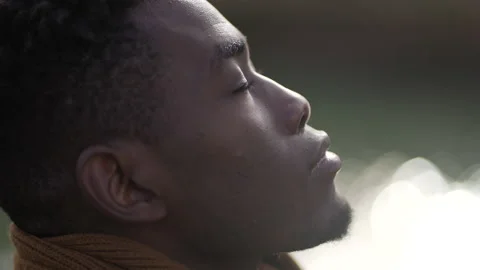 Black man taking a deep breath outside and opening eyes looking up at sky smi Stock Footage 150864091