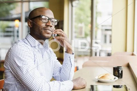 Black Man Talking On Cell Phone In Coffee Shop