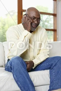 Black Man Talking On Cell Phone On Sofa