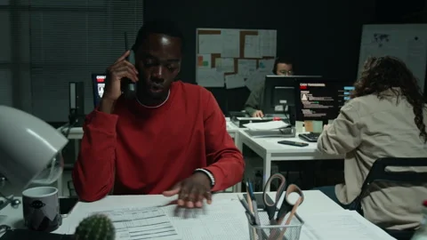 Black Man Talking on Telephone Checking Paperwork in Office Stock Footage 346703525