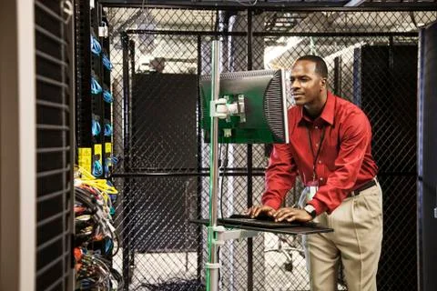 Black man technician doing diagnostic tests on computer servers in server farm. Stock Photos