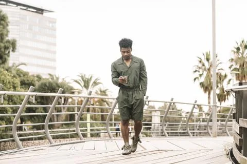 Black man texting on phone while walks in the city Stock Photos