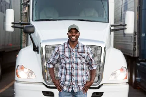 Black man truck driver near his truck parked in a parking lot at a truck stop Stock Photos