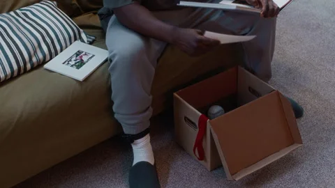 Black Man Under House Arrest Looking Through Old Things from Memory Box Stock Footage 314115582