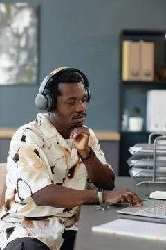 Black Man Using  Computer in Headphones Looking at Screen with Bored Face Stock Photos