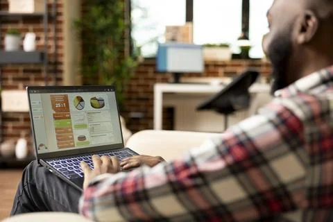 Black man using laptop to draft business reports at home Foto stock