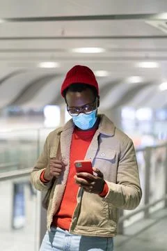 Black man using smart phone in airport terminal, wear face medical mask, using 写真素材