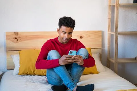 Black man using smartphone on bed Stock Photos