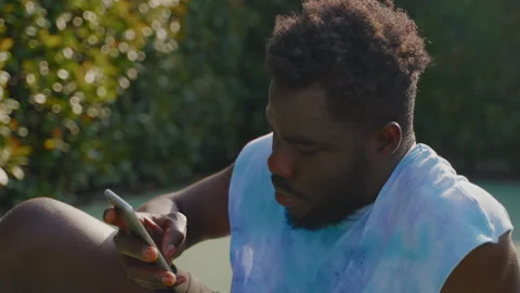 Black man using smartphone outdoors on sunny day Stock Footage 226986043