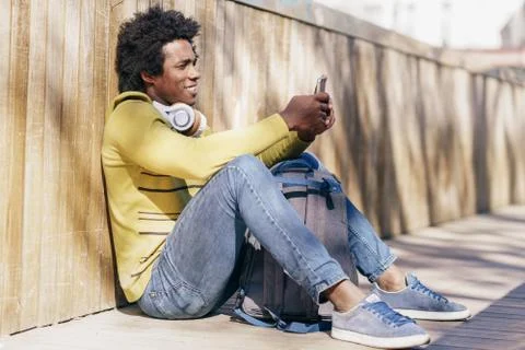 Black man using smartphone resting on the ground. Stock Photos
