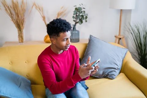 Black man using smartphone on sofa Stock Photos