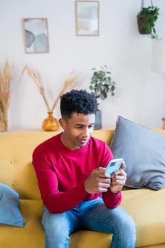 Black man using smartphone on sofa Stock Photos