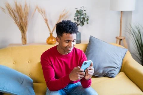 Black man using smartphone on sofa Stock Photos