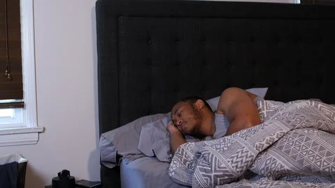 Black man waking up in a bed Stock Footage 128834316