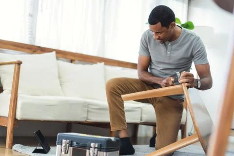 Black man watching online tutorial instructions for assembling furniture Stock Photos