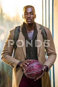 Black man wearing backpack holding basketball Stock Photos