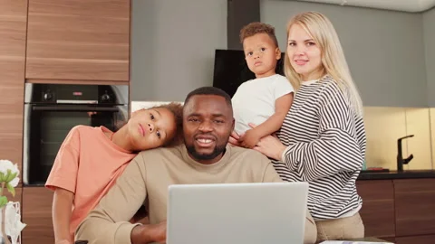 Black man working from home surrounded by loving multiracial family Stock Footage 162140702