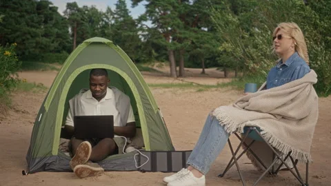 Black Man Working on Laptop in Tent with Woman on Beach Stock Footage 343251285