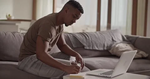 Black man writing down data from laptop Stock Footage 181703324