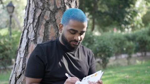 Black man writing notebook in park for thinking and relax for leisure in nature Stock Footage 287487778