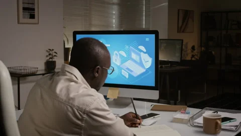 Black Man Writing Notes in Office Working on Cybersecurity Stock Footage 348143392