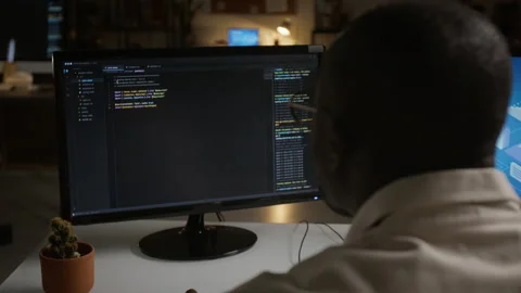Black Man Writing Software Code on Computer Monitor at Night 库存影片 348155432