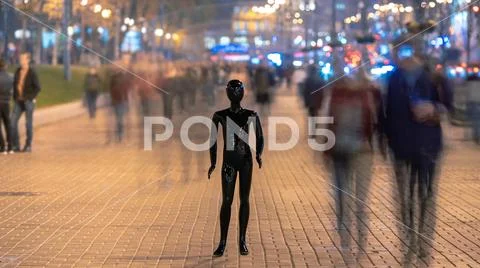 The black mannequin stands on the street among the stream of people Stock Photos