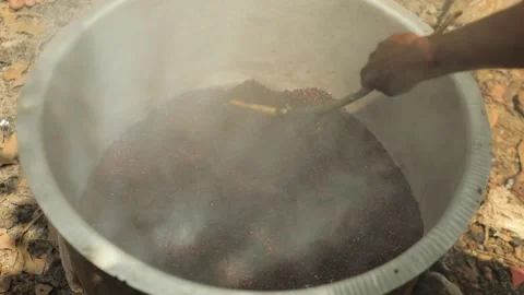 Black man's hand is roasting some seeds in huge aluminium pot with heavy smoke. Stock-Footage 211426460