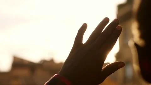 Black man's hand shading face from sunlight at sunset Stock Footage 231550911