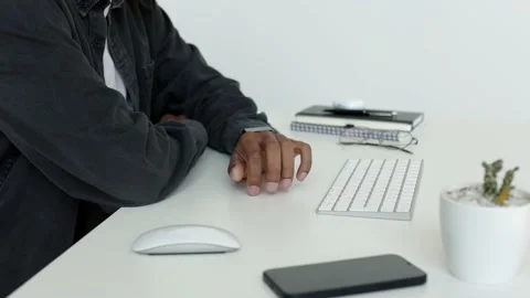 Black man's hand tapping his finger on the white table sitting at the white desk Stock Footage 196127013