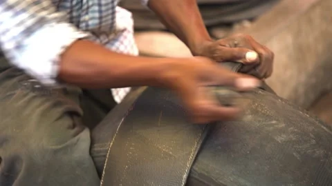 Black man's hands cut black wheel tires in stripes with knife, recycle materials Stock Footage 204130875