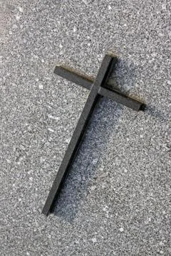 Black marble cross on the background of a gray tombstone Stock Photos