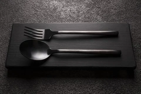 Black matte fork with spoon close-up. on a dark background Stock Photos