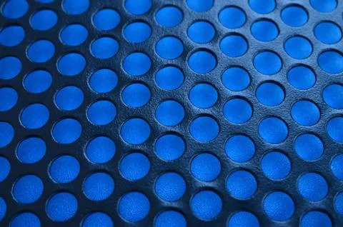 Black metal computer case panel mesh with holes on blue background. Abstract  Stock Photos