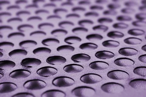 Black metal computer case panel mesh with holes on purple background. Abstr.. 库存照片