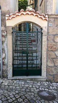 A black metal gate between two walls that leads to a Portuguese-style staircase Foto stock