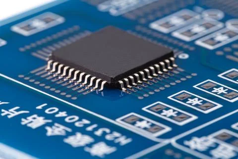 Black microchip with metallic leads sits securely on blue PCB Stock Photos