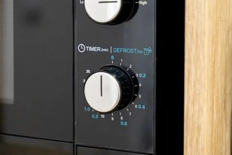 Black microwave control panel with white circular knobs for setting time an.. Stock Photos